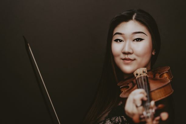 Chloe Kim smiling holding a violin